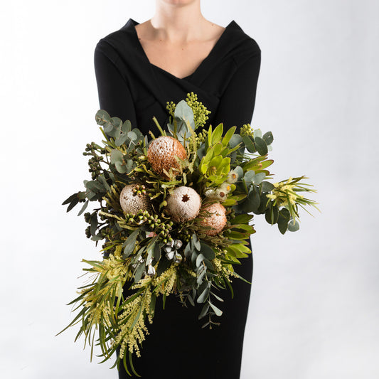 A bouquet of creamy white soft yellows with a mix of textures this  banksia bouquet arranged in a natural loose style accented with lush eucalyptus foliage. To complete the look seasonal Australian flowers are interspersed throughout the bouquet. This may include blooms such as kangaroo paw or wattle depending on the time of year.